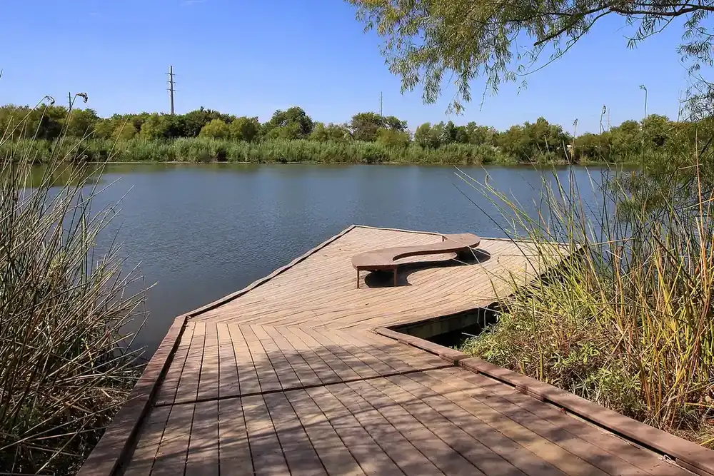 Wooden fishing dock reaching into a pond at Hutto Lake Park in Hutto, Texas