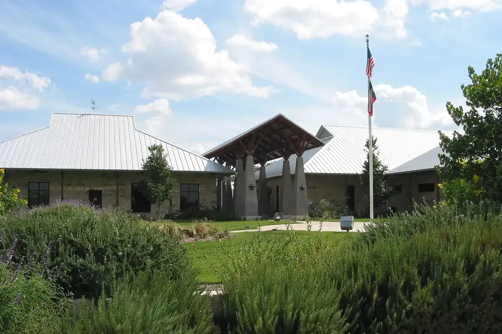 Leander Public Library building with a flag and landscaped garden in Leander, Texas